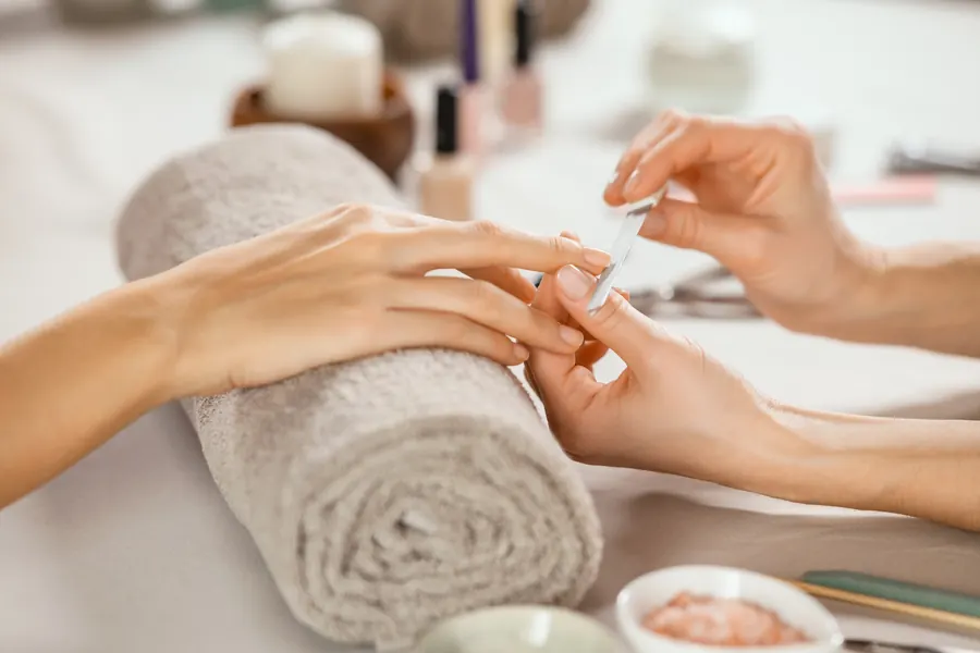 Nail technician filing a client's nails during a manicure