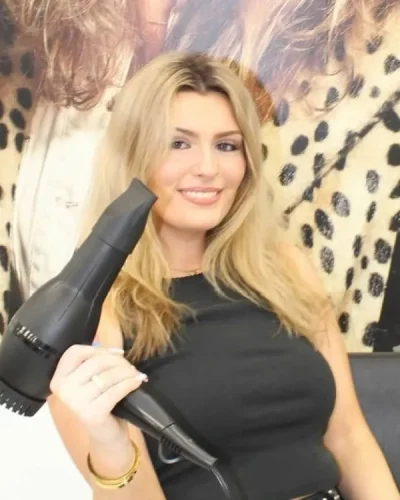 the blonde holding a blow-dryer in the styling chair.
